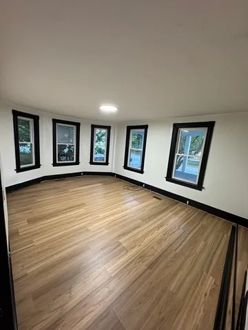 a view of an empty room with window and wooden floor