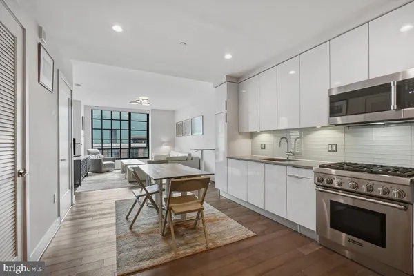 a kitchen with stainless steel appliances granite countertop a stove a sink dishwasher a microwave oven and a refrigerator with wooden floor