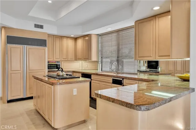 a kitchen with stainless steel appliances granite countertop a refrigerator a stove and a sink
