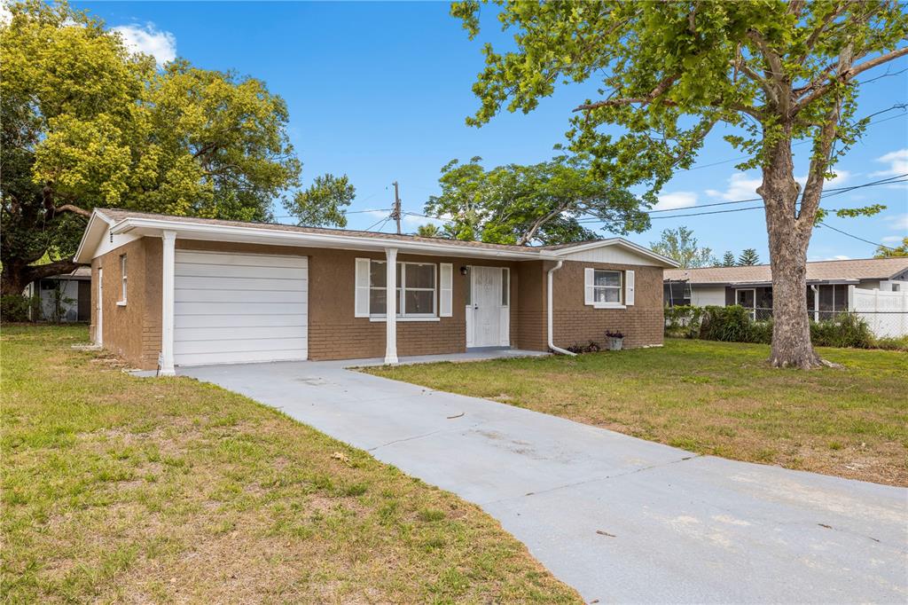 10803 Hyssop Street Port Richey, FL 34668 - Photo 3 of 42 a front view of a house with a garden