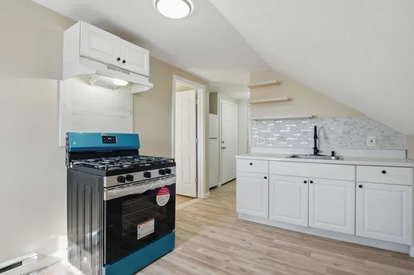 a kitchen with stainless steel appliances a stove a sink dishwasher and a microwave oven with white cabinets