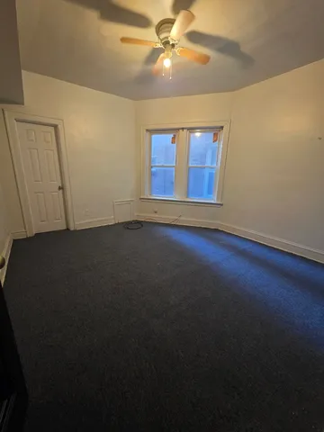 a view of an empty room with window and a ceiling fan