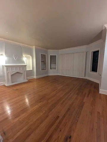 a view of empty room with wooden floor and fireplace