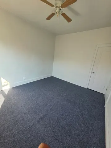 an empty room with a ceiling fan and a window