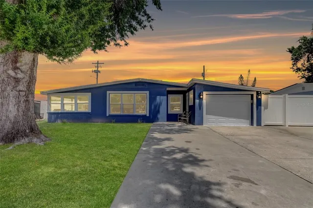 a view of a house with a small yard and a large tree