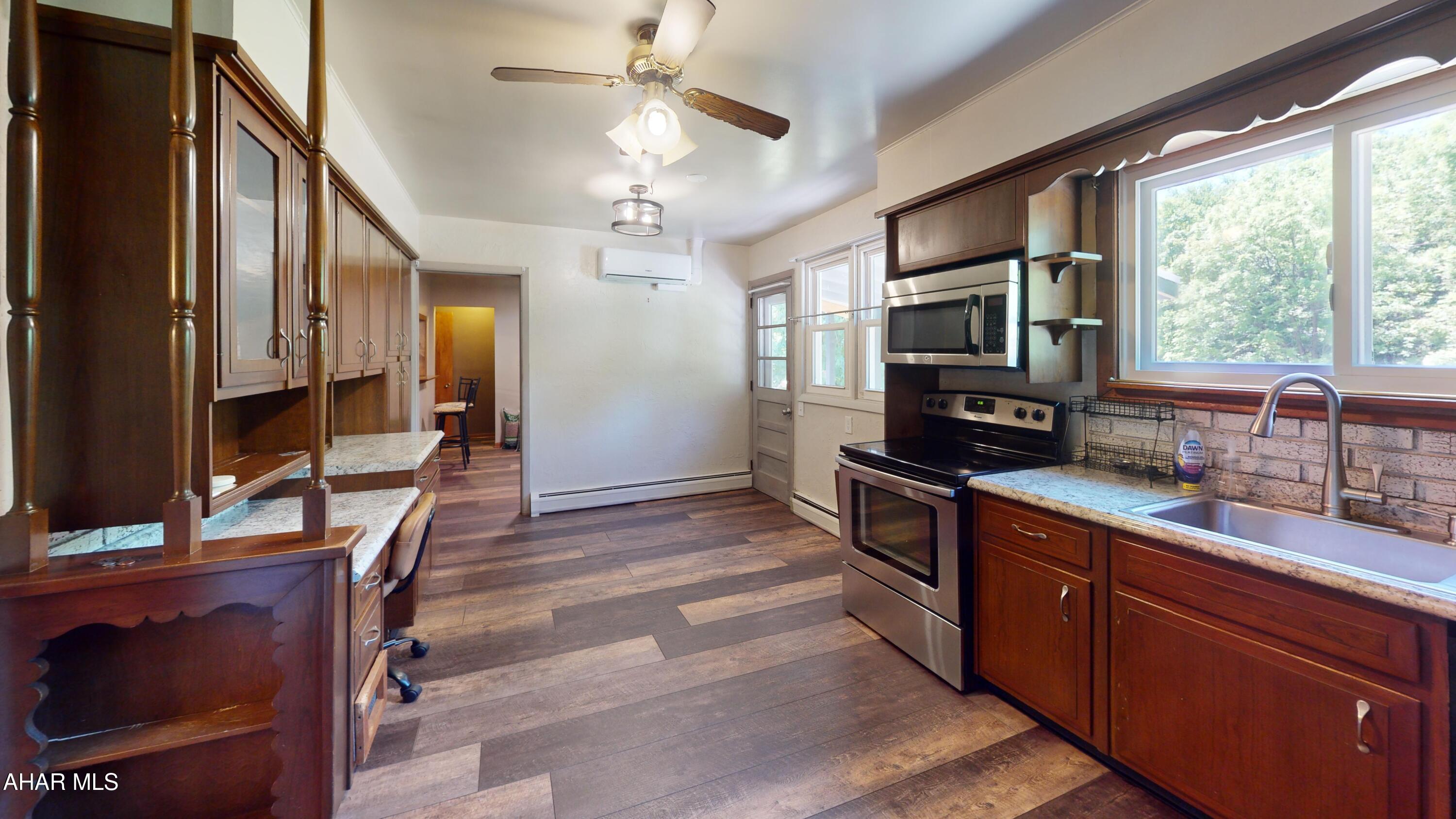 871 Decker Hollow Road Tyrone, PA 16686 - Photo 32 of 35 a kitchen with stainless steel appliances granite countertop a stove top oven a sink dishwasher a dining table and chairs with wooden floor