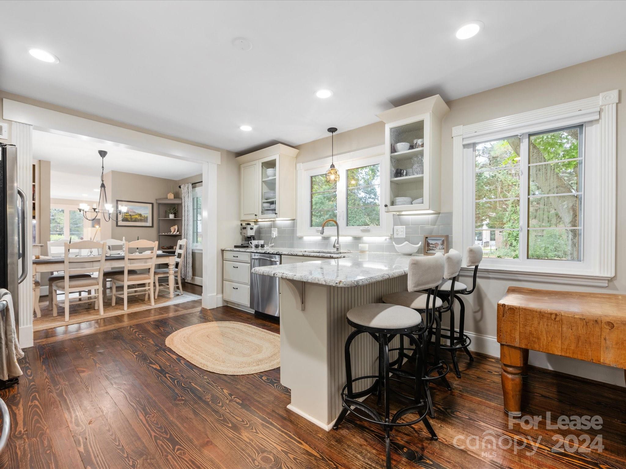 4411 Castleton Road Charlotte, NC 28211 - Photo 15 of 45 a dining hall with stainless steel appliances granite countertop a stove a refrigerator a kitchen island a table and chairs with wooden floor