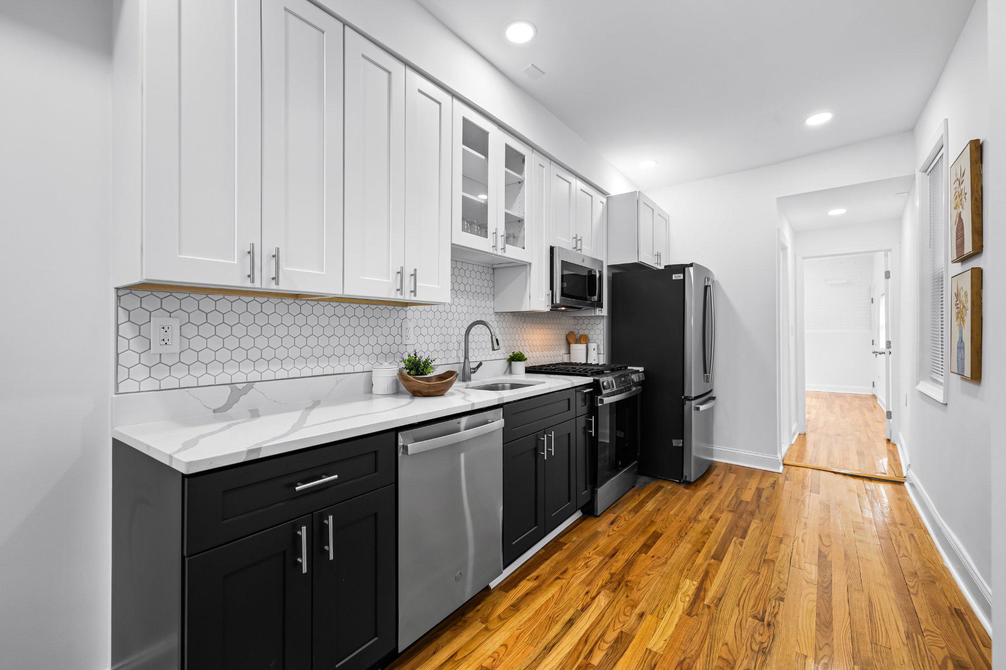 1225 Patapsco Street Baltimore, MD 21230 - Photo 5 of 21 a kitchen with stainless steel appliances granite countertop a refrigerator a sink dishwasher and wooden cabinets with wooden floor