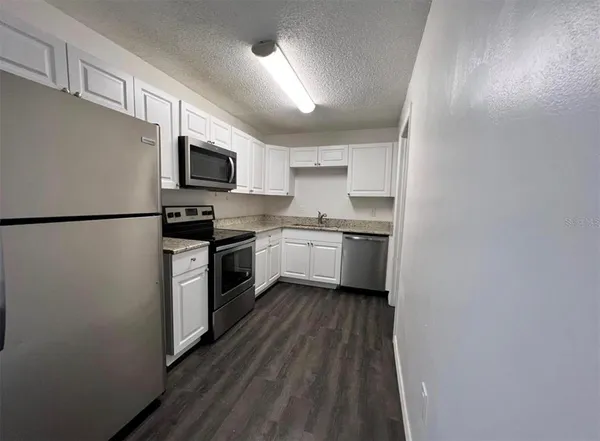 a kitchen with cabinets stainless steel appliances and a refrigerator