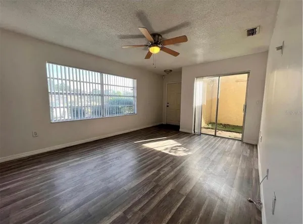 a view of an empty room with wooden floor and a window
