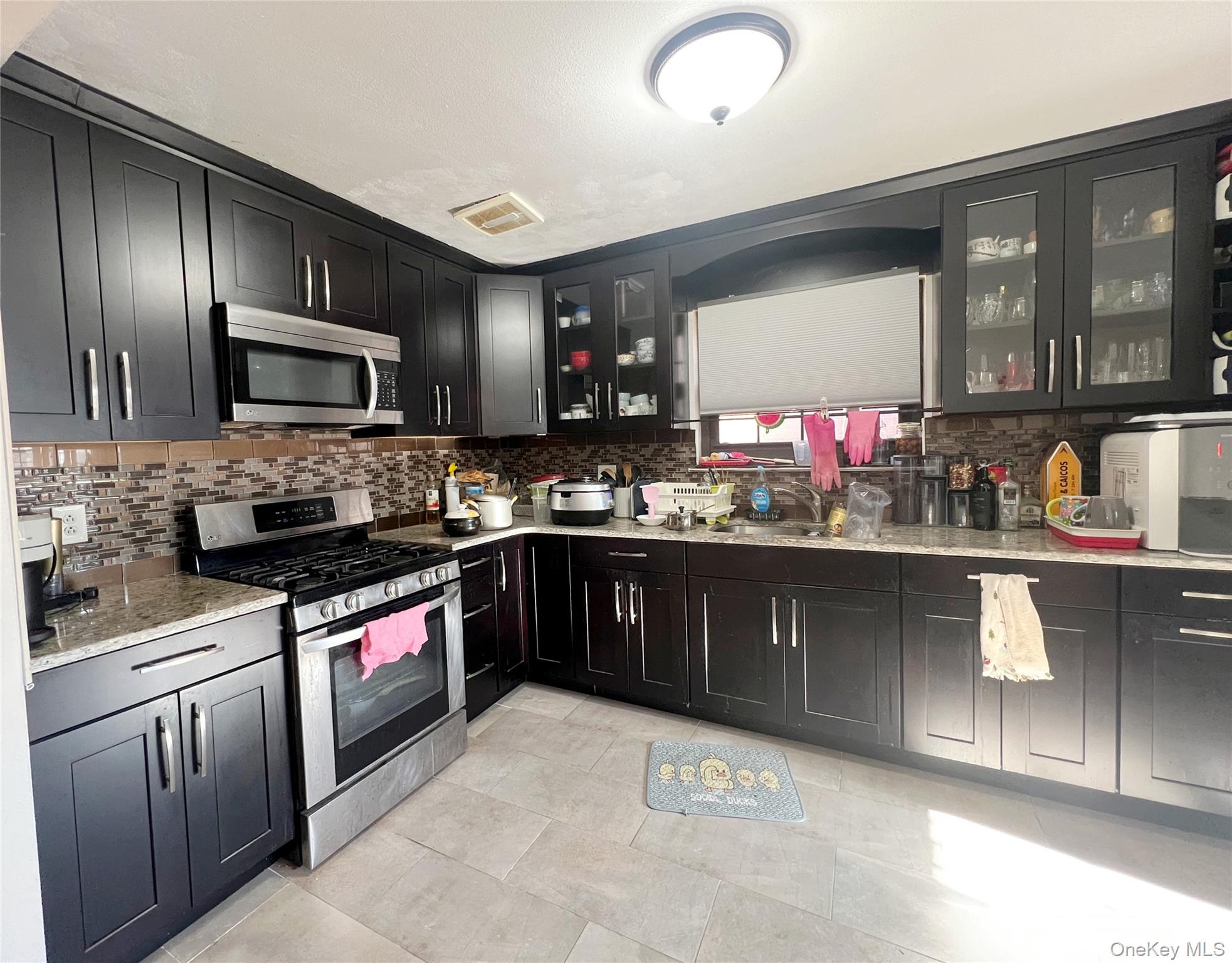 219-74 64th Avenue, Unit 239 Queens, NY 11364 - Photo 3 of 12 a kitchen with stainless steel appliances granite countertop a stove sink and cabinets