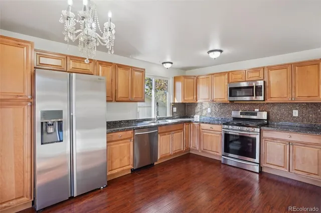 a kitchen with stainless steel appliances granite countertop wooden floors and sink