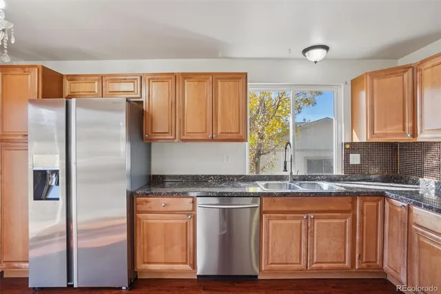 a kitchen with stainless steel appliances granite countertop a stove top oven a refrigerator a sink and dishwasher with wooden floor