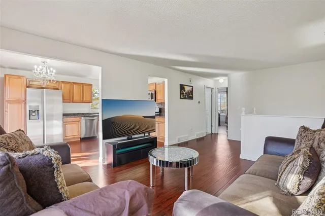 a kitchen with granite countertop wooden floors stainless steel appliances a sink and a window