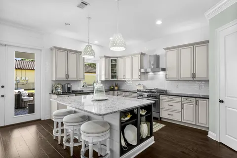 a kitchen with stainless steel appliances granite countertop a stove top oven a refrigerator a sink and dishwasher with wooden floor