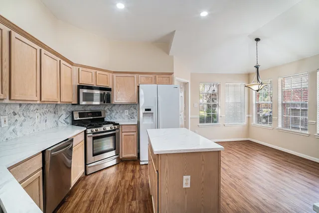 a kitchen with stainless steel appliances granite countertop a refrigerator a stove top oven a sink dishwasher and wooden floor