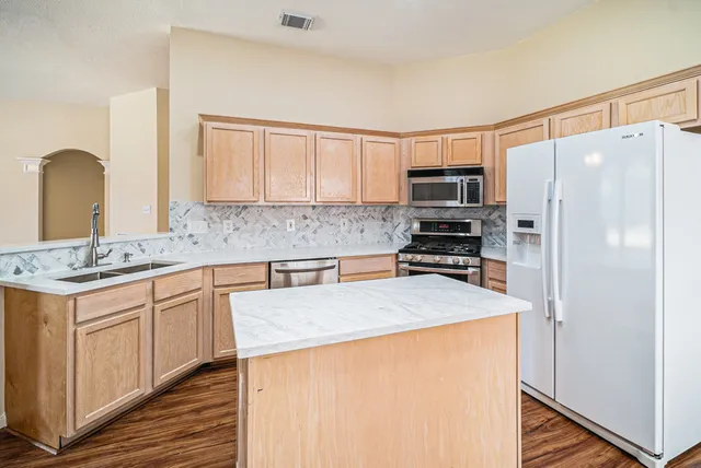 a kitchen with granite countertop a refrigerator stove top oven and sink