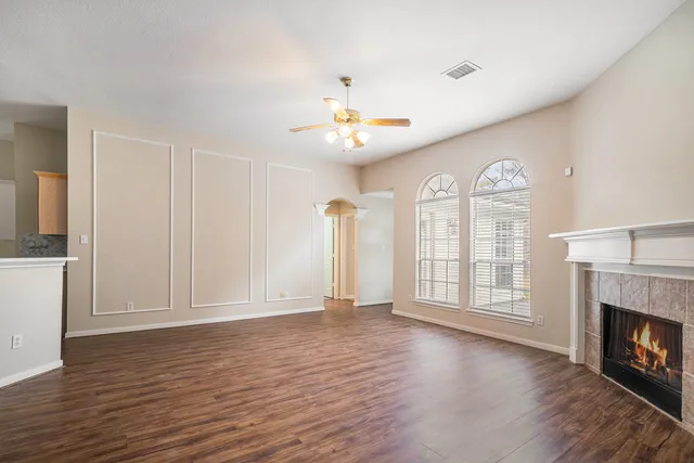 a view of an empty room with window and wooden floor