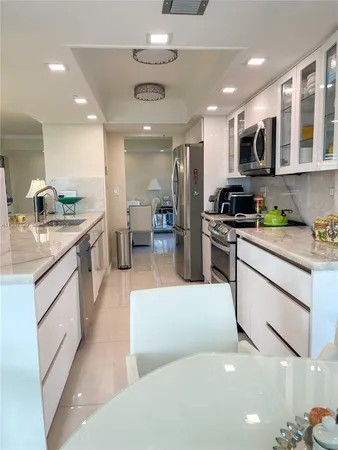 a large white kitchen with stainless steel appliances granite countertop a stove and a sink