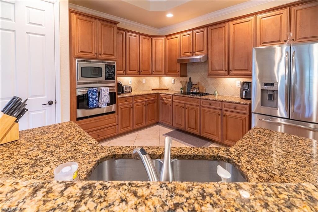 9458 Piacere Way Naples, FL 34113 - Photo 12 of 50 a kitchen with stainless steel appliances granite countertop a refrigerator sink and stove