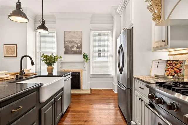 a kitchen with stainless steel appliances granite countertop wooden floors stove and white cabinets