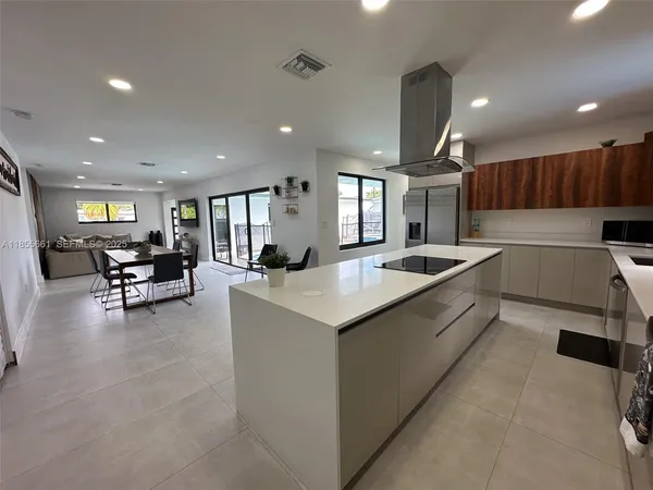 a large white kitchen with a large island in the center