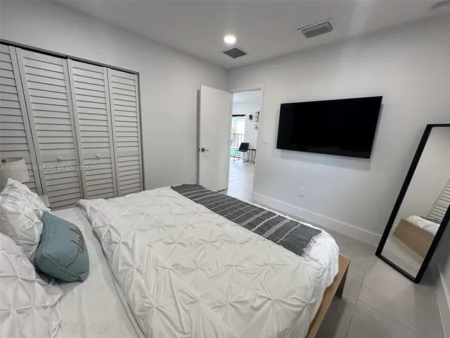a bedroom with a bed a flat screen tv and a large window