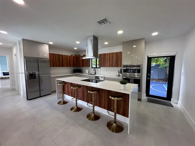 a kitchen with stainless steel appliances kitchen island granite countertop a refrigerator and a sink