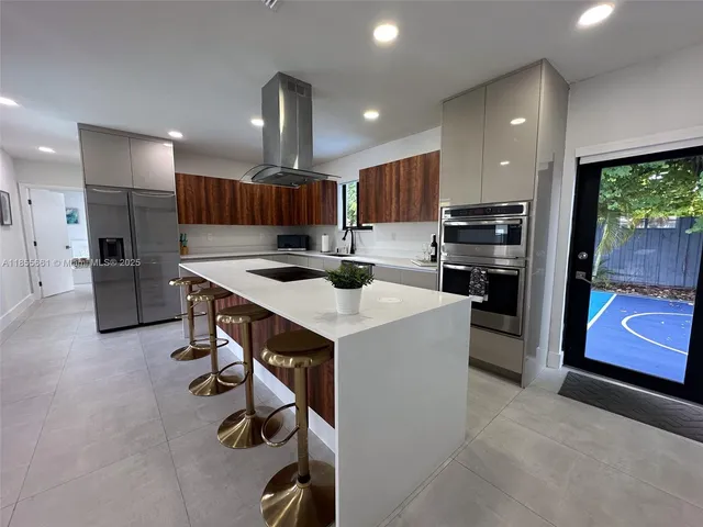 a kitchen with stainless steel appliances kitchen island a table chairs refrigerator and sink