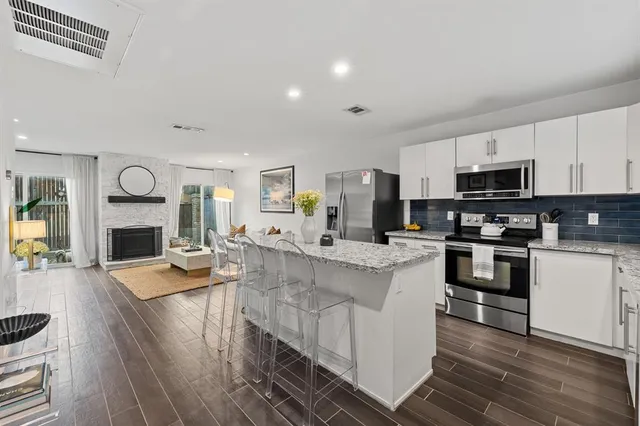 a kitchen with stainless steel appliances a stove top oven a sink dishwasher and a refrigerator with wooden floor