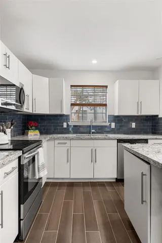 a kitchen with granite countertop a stove sink and cabinets