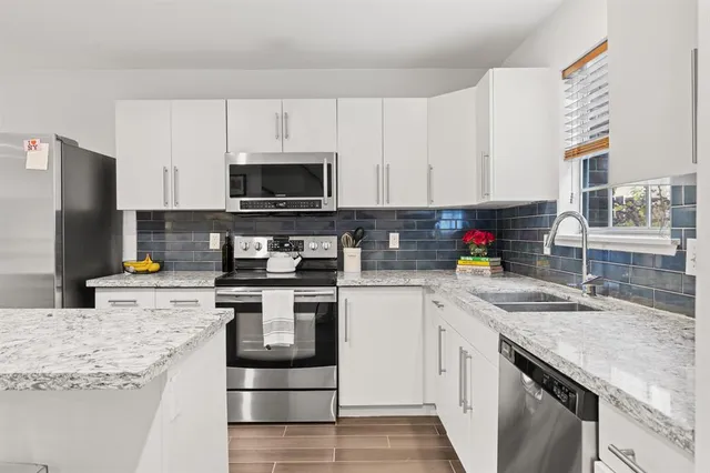 a kitchen with stainless steel appliances granite countertop a sink stove microwave and refrigerator