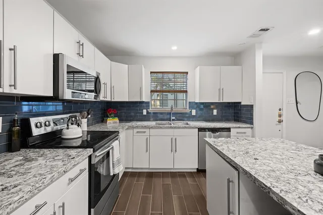 a kitchen with stainless steel appliances granite countertop a sink stove and refrigerator