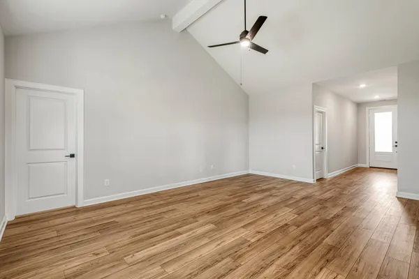 a view of empty room with wooden floor and ceiling fan