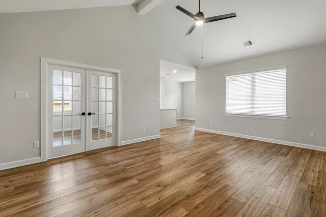 a view of empty room with wooden floor and fan