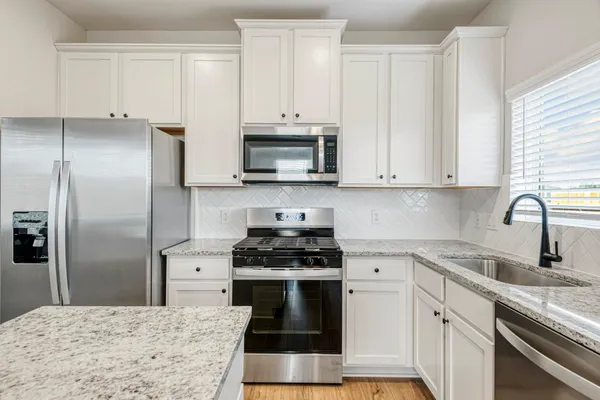 a kitchen with stainless steel appliances granite countertop a stove a refrigerator and a sink