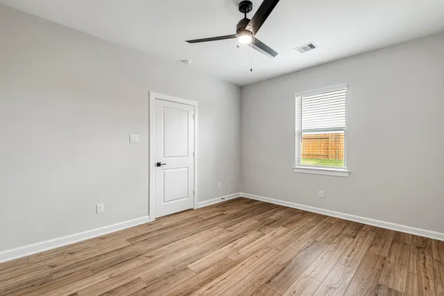 a view of empty room with wooden floor and fan