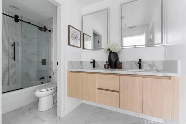 a bathroom with a double vanity sink toilet and shower