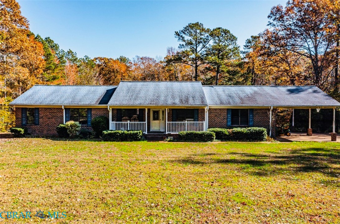Ranch-style house featuring a porch, an attached carport, a front yard, and a shingled roof