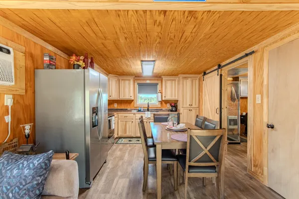 a kitchen with stainless steel appliances a dining table chairs and a refrigerator