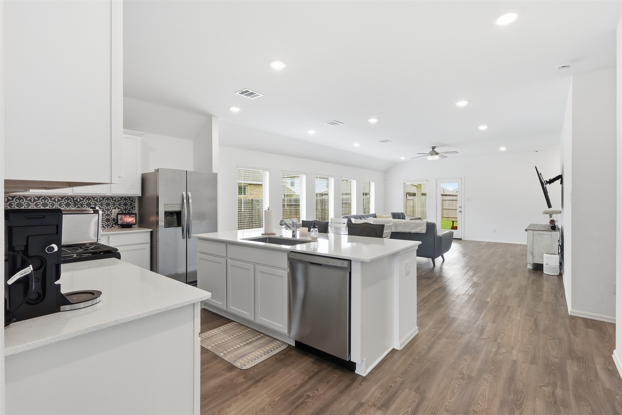 3727 Moss Hl Road Rosenberg, TX 77469 - Photo 32 of 32 The open-concept floor plan seamlessly ties the kitchen, dining, and living areas together. the kitchen features white cabinets, a large island with breakfast bar seating, stainless steel appliances, and stylish backsplash.