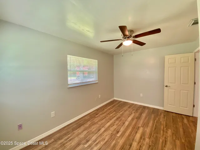 a view of a big room with wooden floor and a ceiling fan