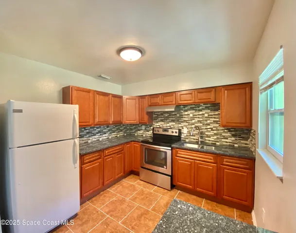 a kitchen with stainless steel appliances granite countertop a refrigerator sink and white cabinets