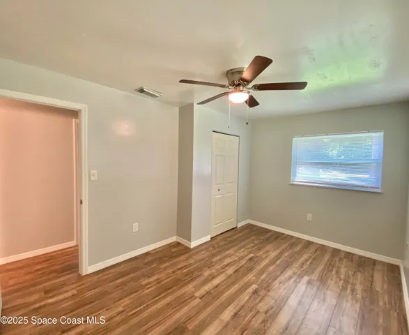 a view of a room with wooden floor and a ceiling fan