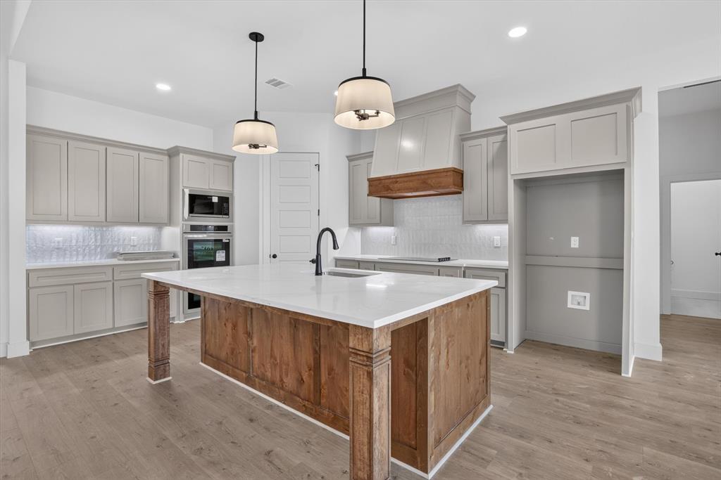 471 Red Bird Drive Springtown, TX 76082 - Photo 11 of 35 Kitchen featuring a wood-finish island with a white countertop, light gray cabinetry, built-in stainless steel appliances, and wood-finish flooring