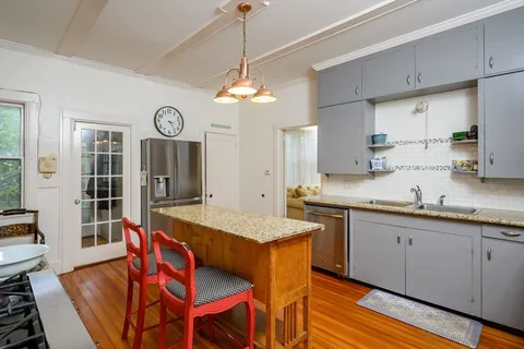 a very nice looking kitchen with granite countertop a stove a sink a dining table and chairs with wooden floor