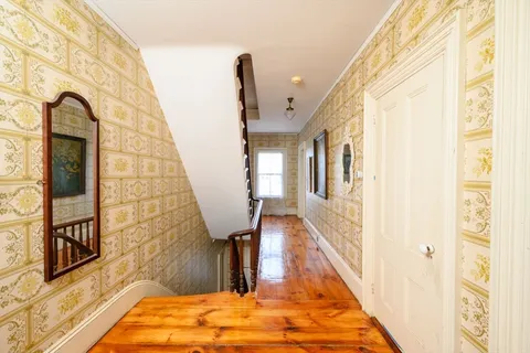 a view of a hallway with wooden floor and staircase
