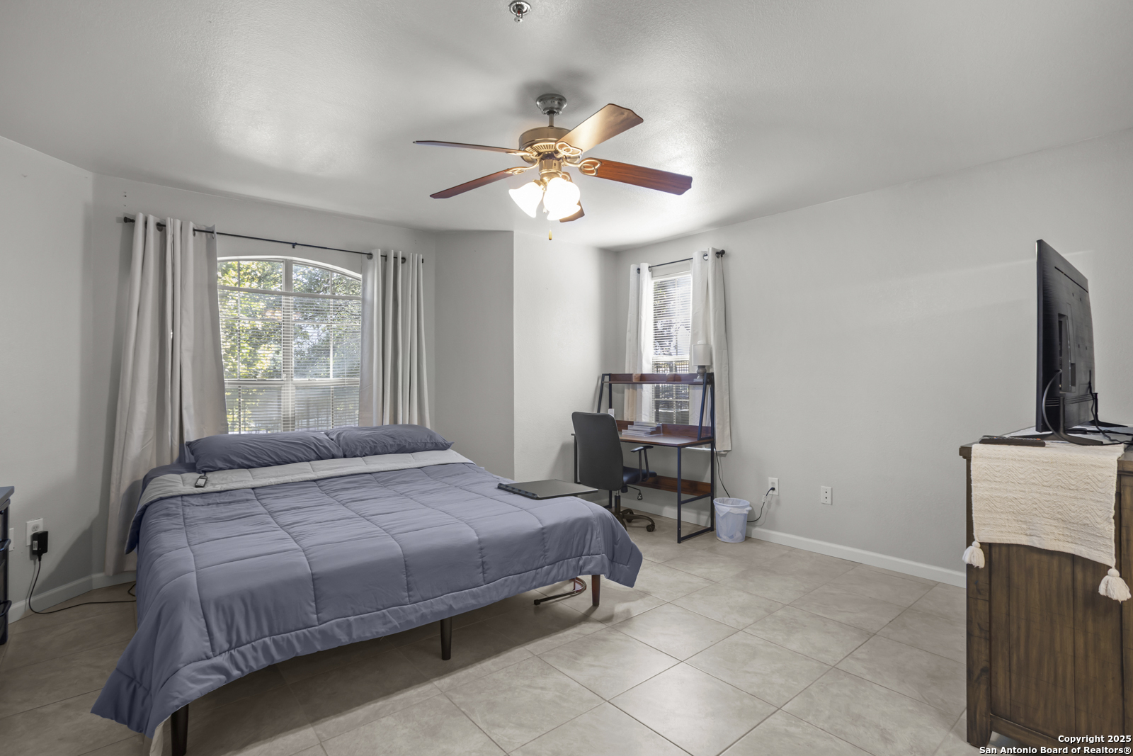 7323 Snowden Road, Unit 1102 San Antonio, TX 78229 - Photo 14 of 27 a bedroom with a bed a chandelier and a flat screen tv