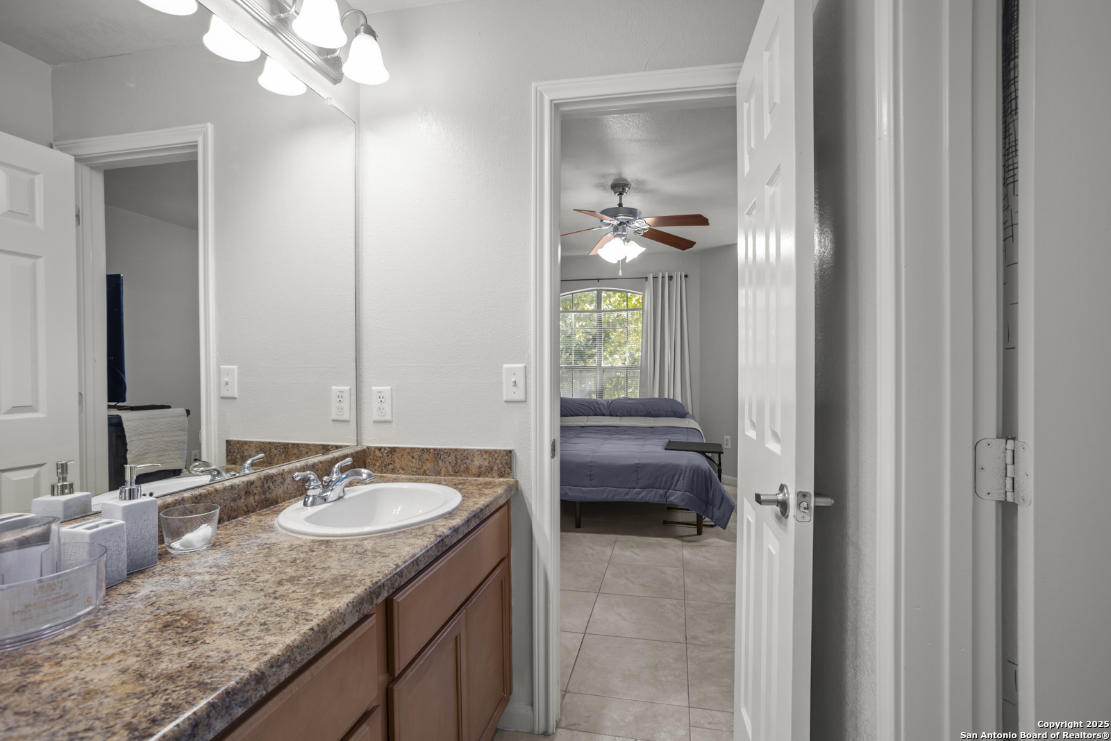 7323 Snowden Road, Unit 1102 San Antonio, TX 78229 - Photo 20 of 27 a en suite bathroom with a granite countertop sink a mirror and a vanity