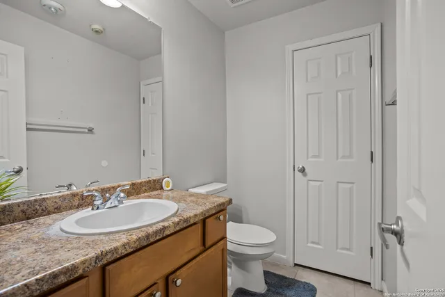 a bathroom with a granite countertop sink a toilet and a mirror